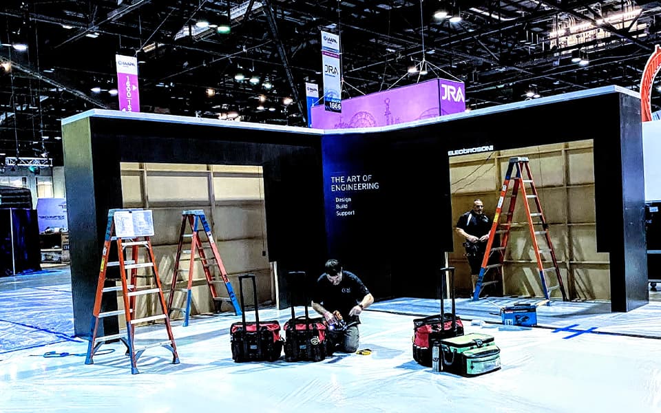 Crew installing a custom exhibit structure on the show floor
