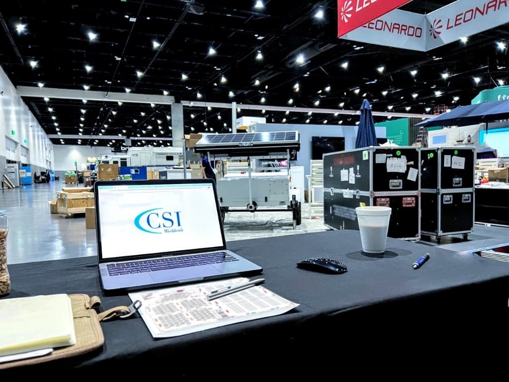 CSI project manager's on-site desk with laptop, floor plan, and show equipment on the hall floor